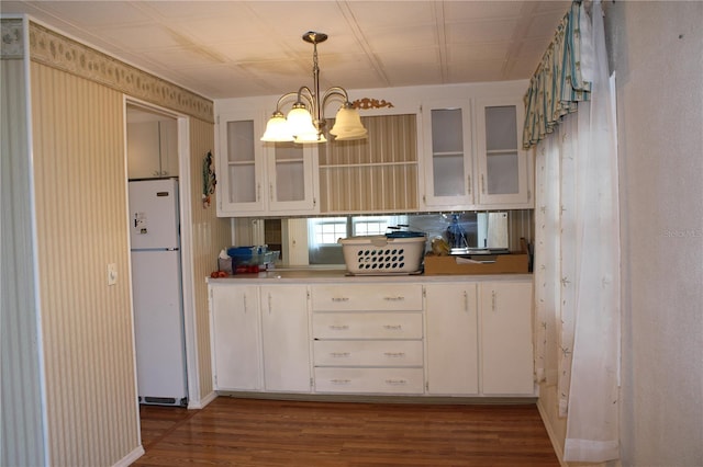 kitchen with pendant lighting, white cabinetry, white refrigerator, a notable chandelier, and dark wood-type flooring