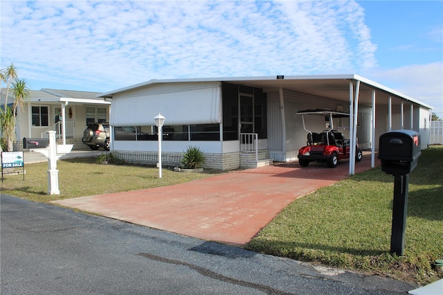 manufactured / mobile home with a carport and a front yard