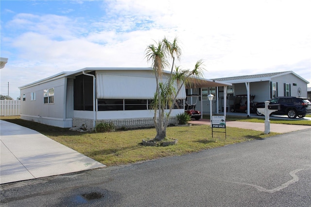 manufactured / mobile home with a sunroom and a front lawn