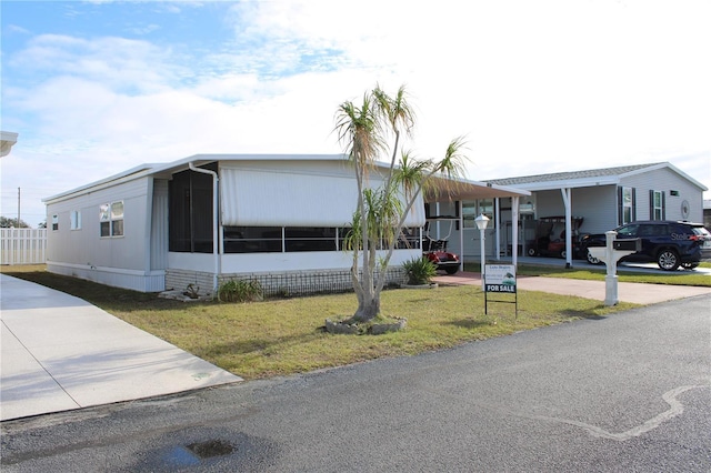 manufactured / mobile home featuring a carport, a sunroom, and a front lawn