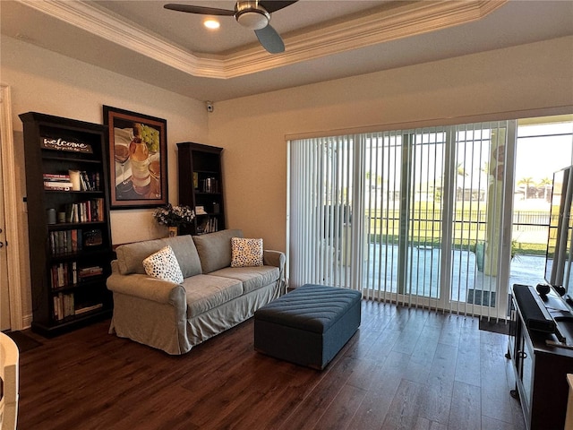 living room with a raised ceiling, crown molding, dark hardwood / wood-style floors, and ceiling fan