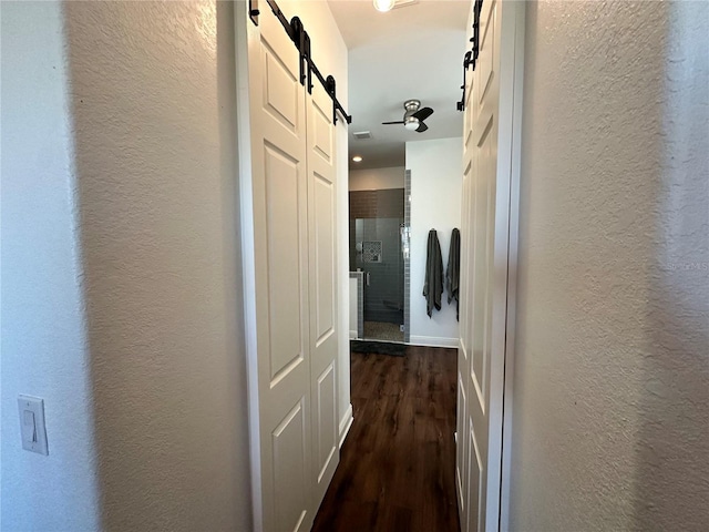 corridor featuring a barn door and dark hardwood / wood-style floors