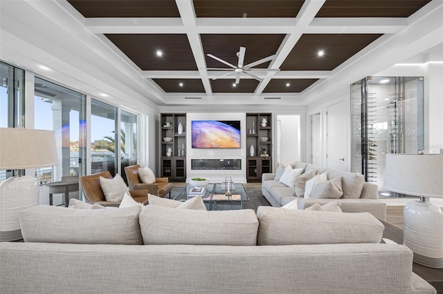 cinema with ceiling fan, wood-type flooring, beam ceiling, and coffered ceiling