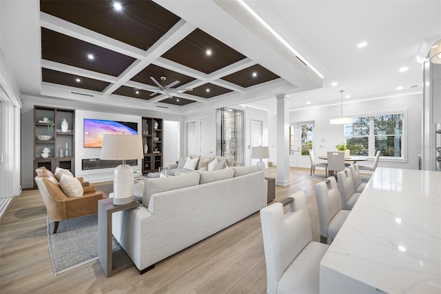 living room featuring light wood-type flooring, beam ceiling, ornamental molding, coffered ceiling, and decorative columns