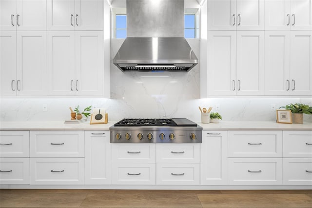 kitchen featuring stainless steel gas stovetop, backsplash, white cabinets, and island range hood