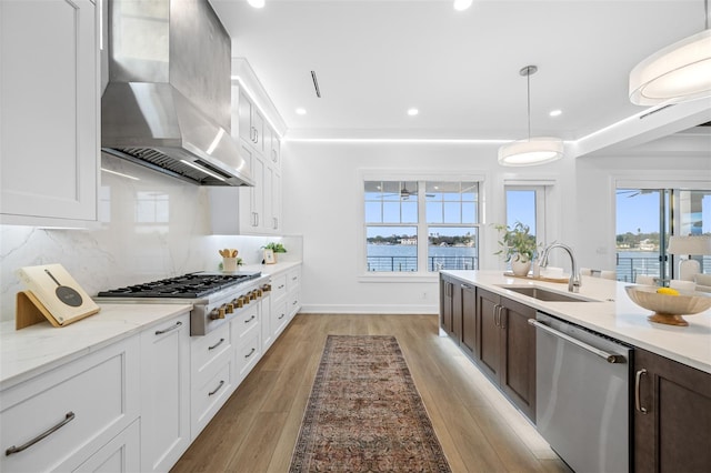 kitchen with white cabinetry, wall chimney range hood, stainless steel appliances, and a water view