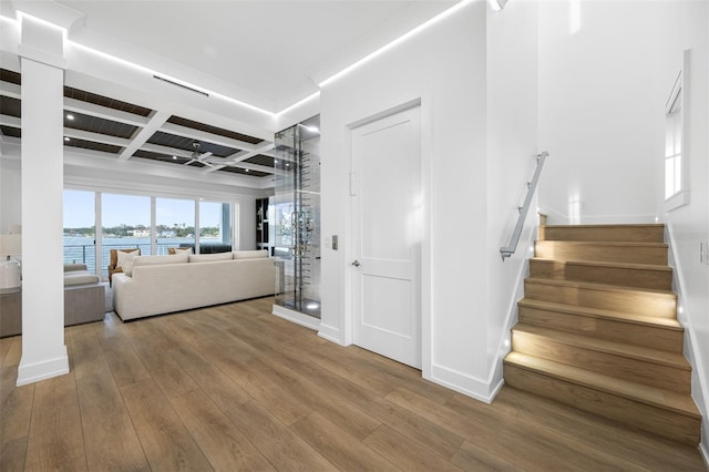 staircase featuring hardwood / wood-style floors, beam ceiling, a water view, and coffered ceiling