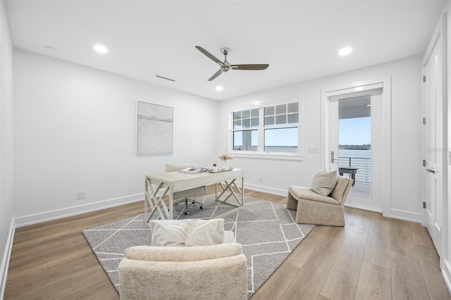 office space with hardwood / wood-style flooring, a water view, and ceiling fan