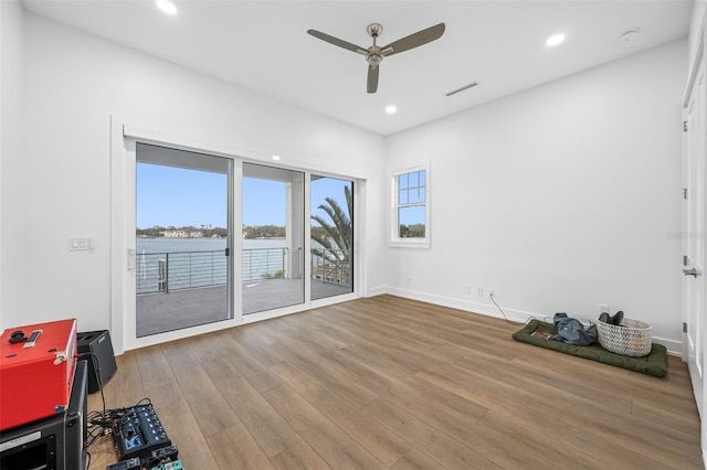 unfurnished room featuring ceiling fan, wood-type flooring, and a water view