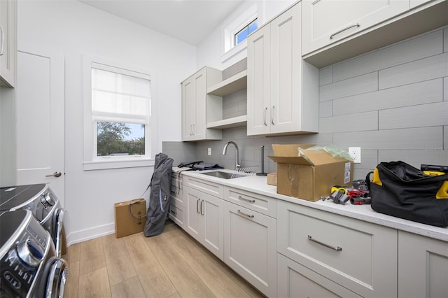 kitchen featuring sink, washer and clothes dryer, white cabinets, and tasteful backsplash