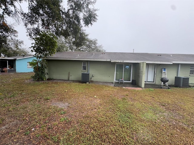 back of property with central AC unit and a yard