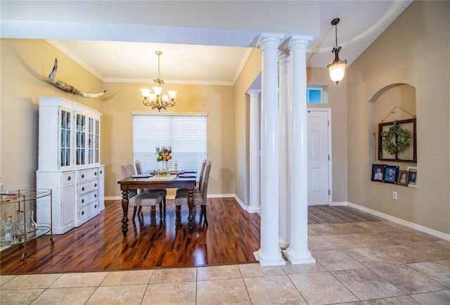 tiled dining room featuring an inviting chandelier, ornamental molding, decorative columns, and lofted ceiling