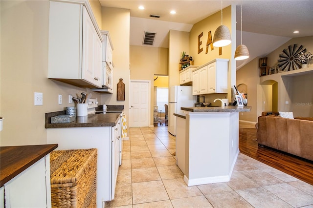 kitchen with light tile patterned flooring, kitchen peninsula, pendant lighting, white appliances, and white cabinets