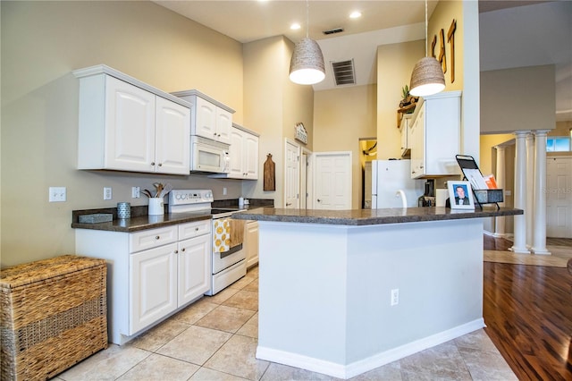 kitchen featuring white appliances, white cabinets, light tile patterned flooring, kitchen peninsula, and ornate columns