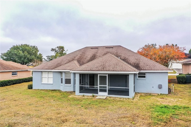 back of property with a sunroom and a lawn