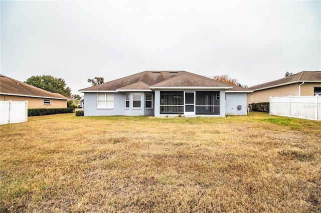 rear view of house featuring a sunroom and a lawn