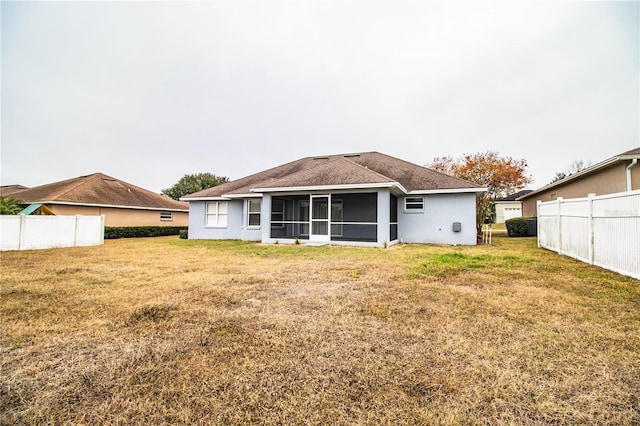 back of property with a yard and a sunroom