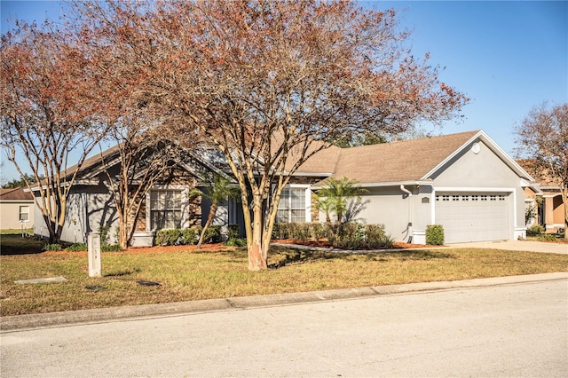 single story home with an attached garage, concrete driveway, a front yard, and stucco siding