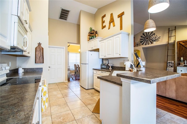 kitchen with white appliances, a peninsula, visible vents, a sink, and dark countertops