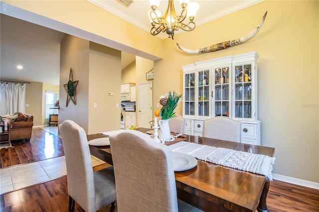 dining space featuring crown molding, baseboards, a chandelier, and wood finished floors