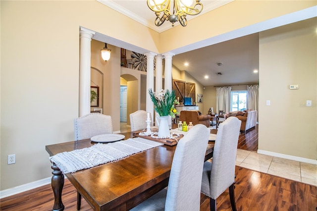 dining space with crown molding, ornate columns, arched walkways, and wood finished floors