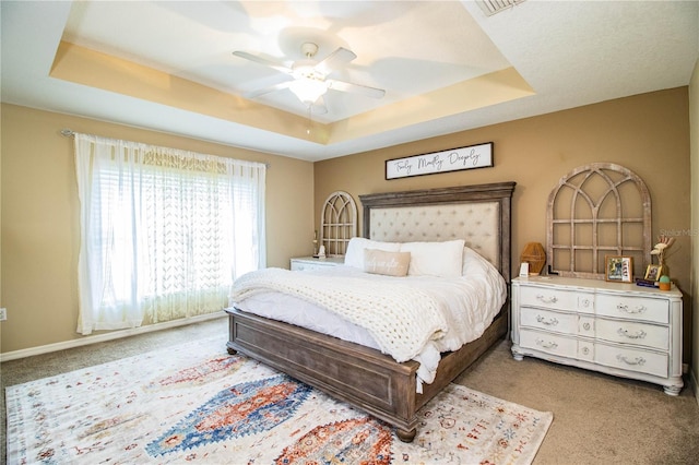 bedroom with baseboards, a raised ceiling, carpet flooring, and a ceiling fan