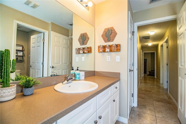 bathroom with visible vents, tile patterned floors, vanity, and a textured ceiling