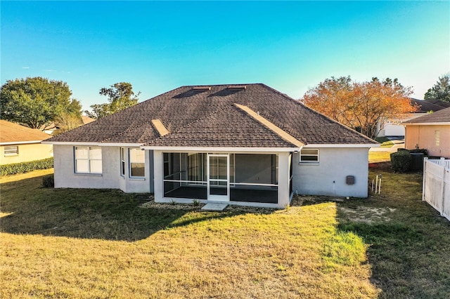 rear view of property featuring a sunroom, a yard, stucco siding, roof with shingles, and fence