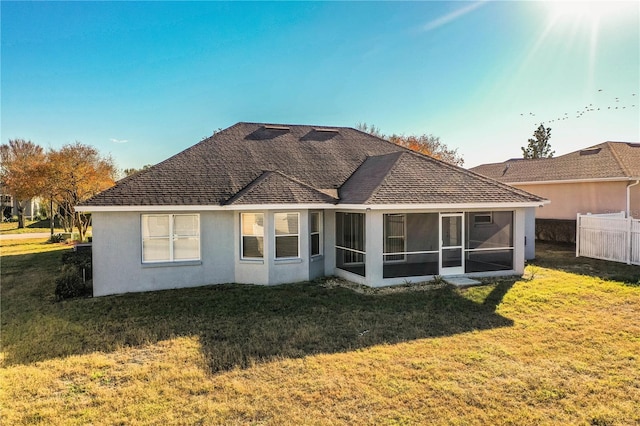 back of property featuring a sunroom, a yard, stucco siding, roof with shingles, and fence