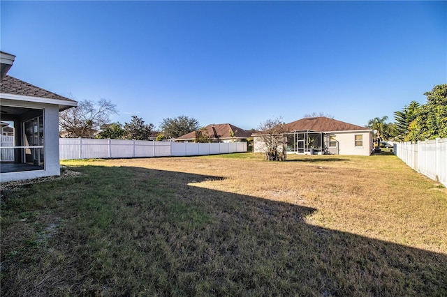 view of yard featuring a fenced backyard and a sunroom