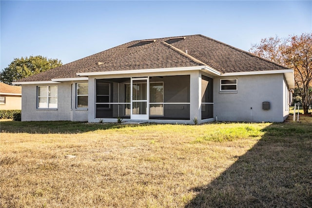 rear view of house with roof with shingles, stucco siding, a sunroom, and a lawn