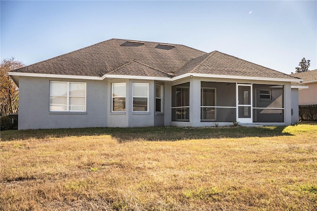 back of property featuring a sunroom, a yard, a shingled roof, and stucco siding