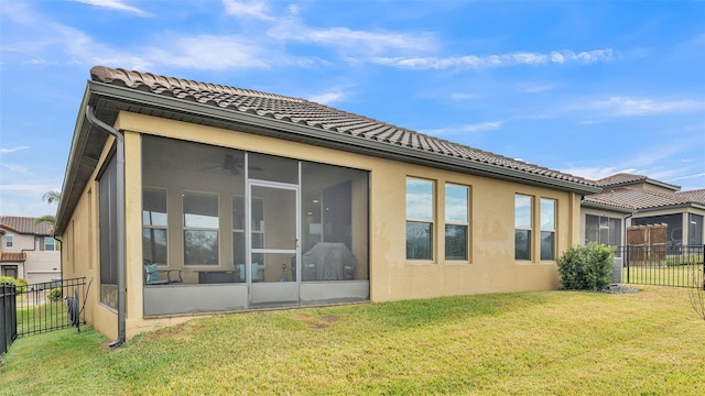 back of property with a lawn and a sunroom