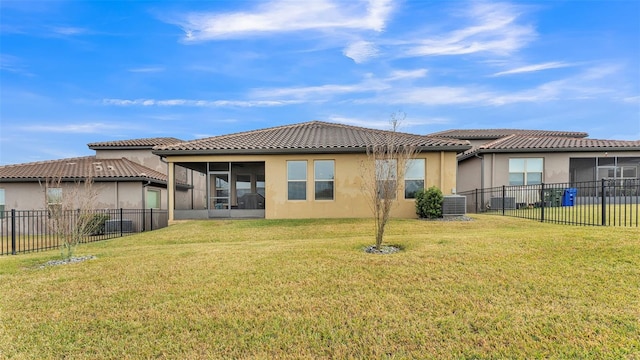 rear view of property featuring a sunroom, a lawn, and cooling unit