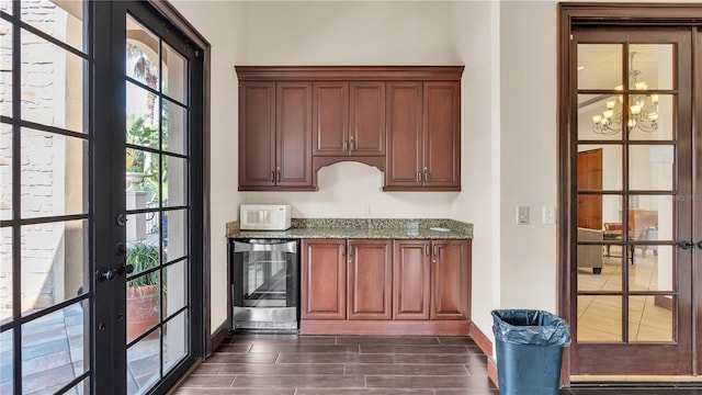 bar featuring light stone countertops, beverage cooler, a notable chandelier, and french doors