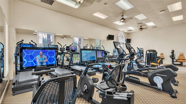 exercise room with light colored carpet, a drop ceiling, and ceiling fan