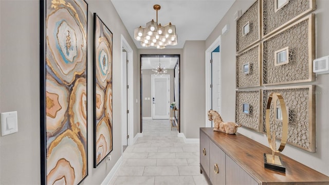 hallway featuring an inviting chandelier and light tile patterned flooring