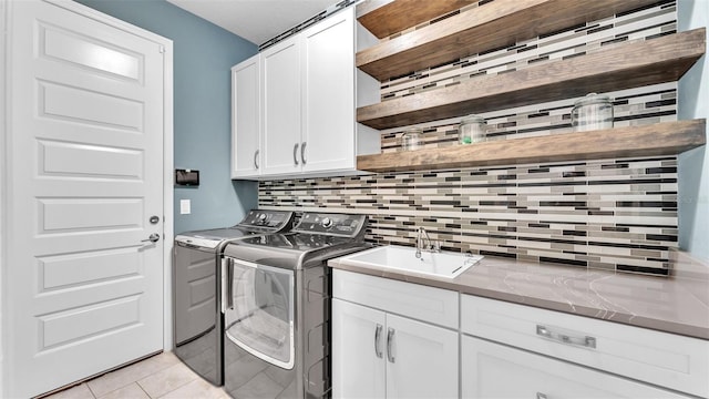 washroom featuring cabinets, sink, light tile patterned floors, and washer and clothes dryer