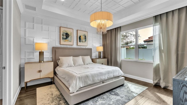 bedroom featuring an inviting chandelier, ornamental molding, dark hardwood / wood-style floors, and a raised ceiling