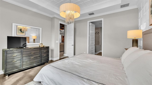 bedroom featuring crown molding, a tray ceiling, dark hardwood / wood-style floors, and a chandelier