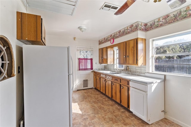 kitchen featuring white refrigerator, ceiling fan, sink, and decorative backsplash