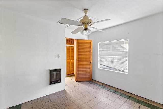 empty room with ceiling fan, a fireplace, and heating unit