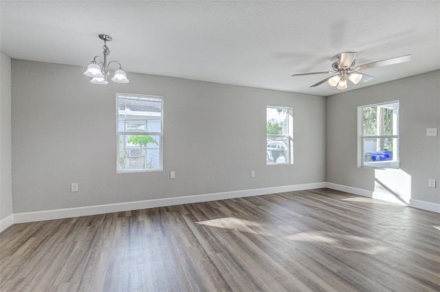 spare room featuring hardwood / wood-style flooring and ceiling fan with notable chandelier