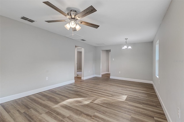 empty room featuring ceiling fan with notable chandelier and light hardwood / wood-style floors