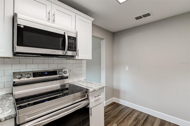 kitchen with appliances with stainless steel finishes, white cabinetry, tasteful backsplash, dark hardwood / wood-style floors, and light stone counters