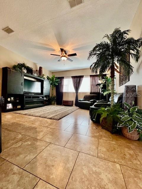 tiled living room featuring ceiling fan and a textured ceiling