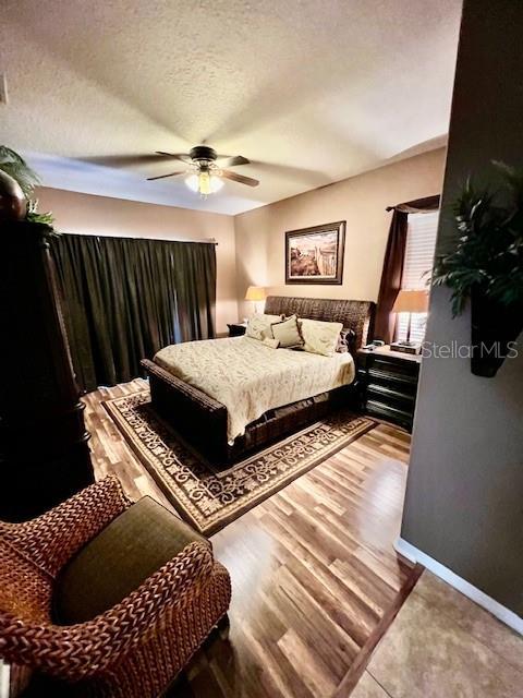 bedroom with hardwood / wood-style flooring, ceiling fan, and a textured ceiling