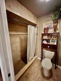 bathroom featuring tile patterned flooring, toilet, and walk in shower