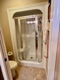 bathroom featuring toilet and a shower with shower door