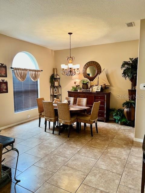 dining space featuring an inviting chandelier, light tile patterned floors, and a textured ceiling